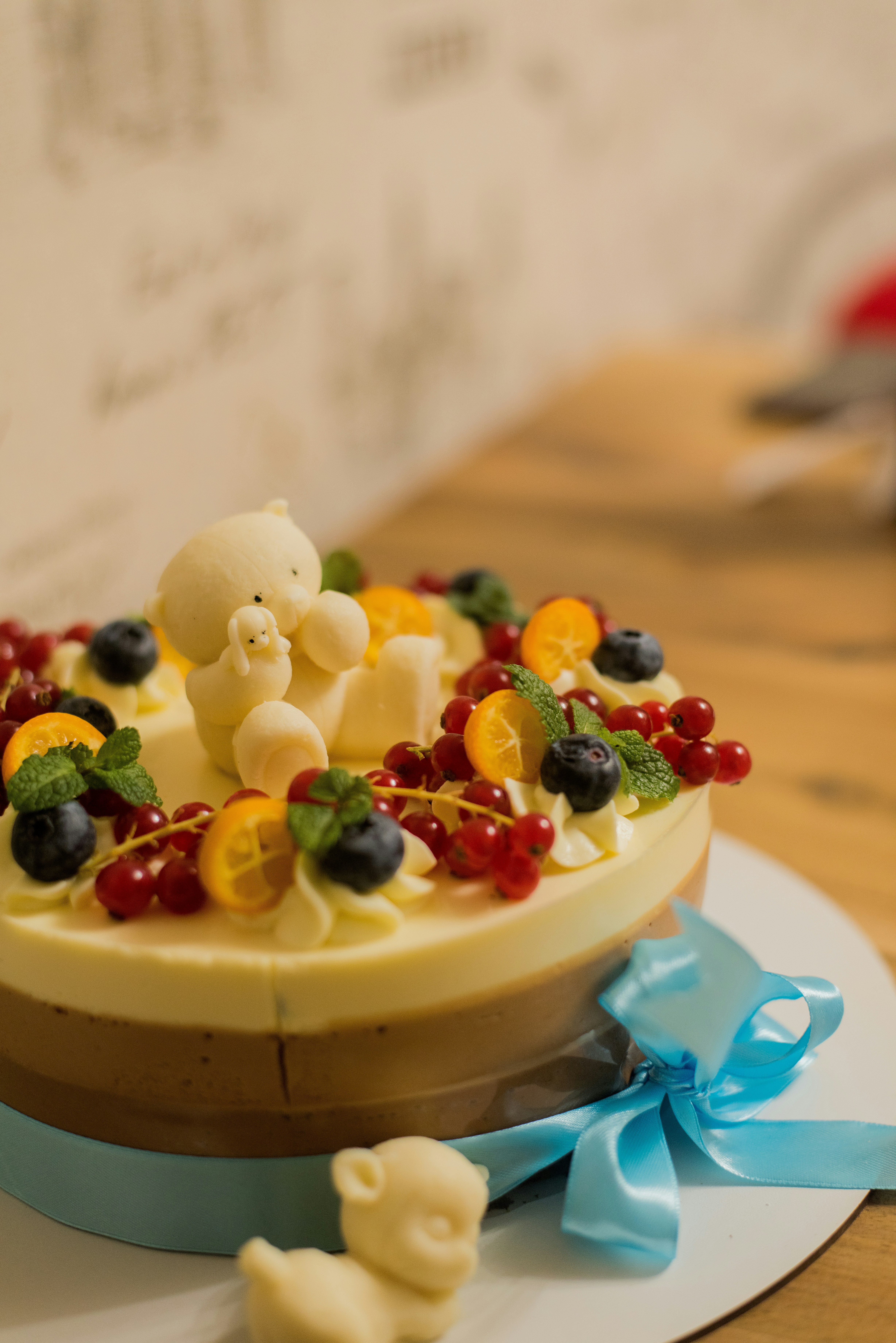 Seasonal fruit cake with glossy mirror glaze and fresh tropical fruits on white surface