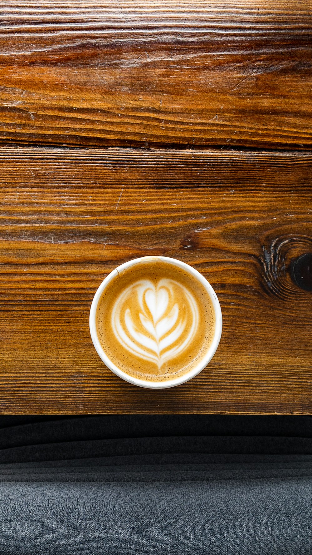 a cup of latte art on a wooden table