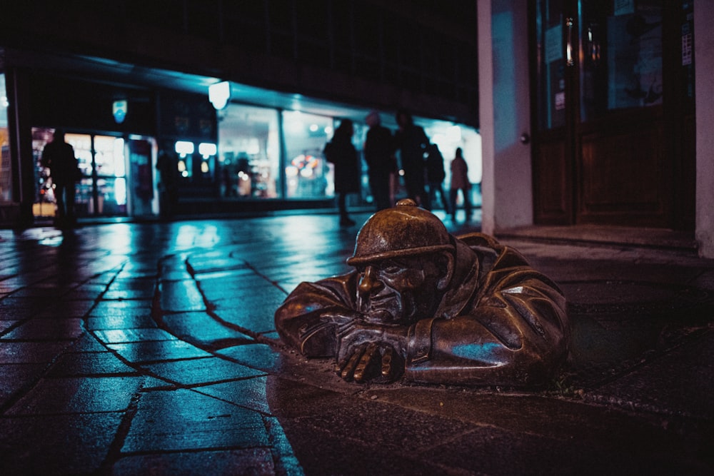 a bronze statue of a man sitting on the ground