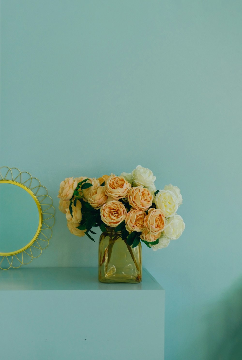 Un jarrón lleno de flores junto a un espejo