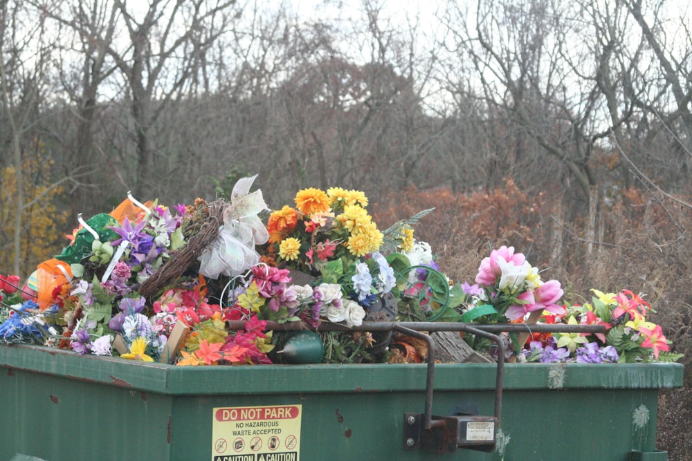 a green dumpster filled with lots of flowers