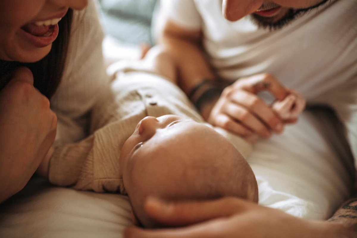 A mother and father holding their newborn baby together, looking tired but happy