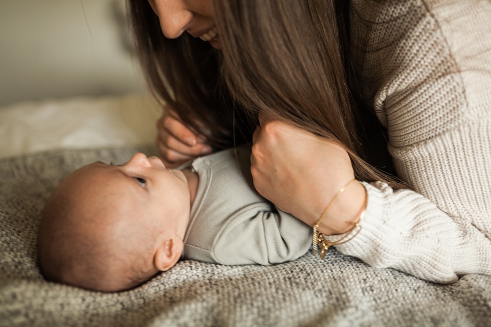 a woman holding a baby while laying on a bed