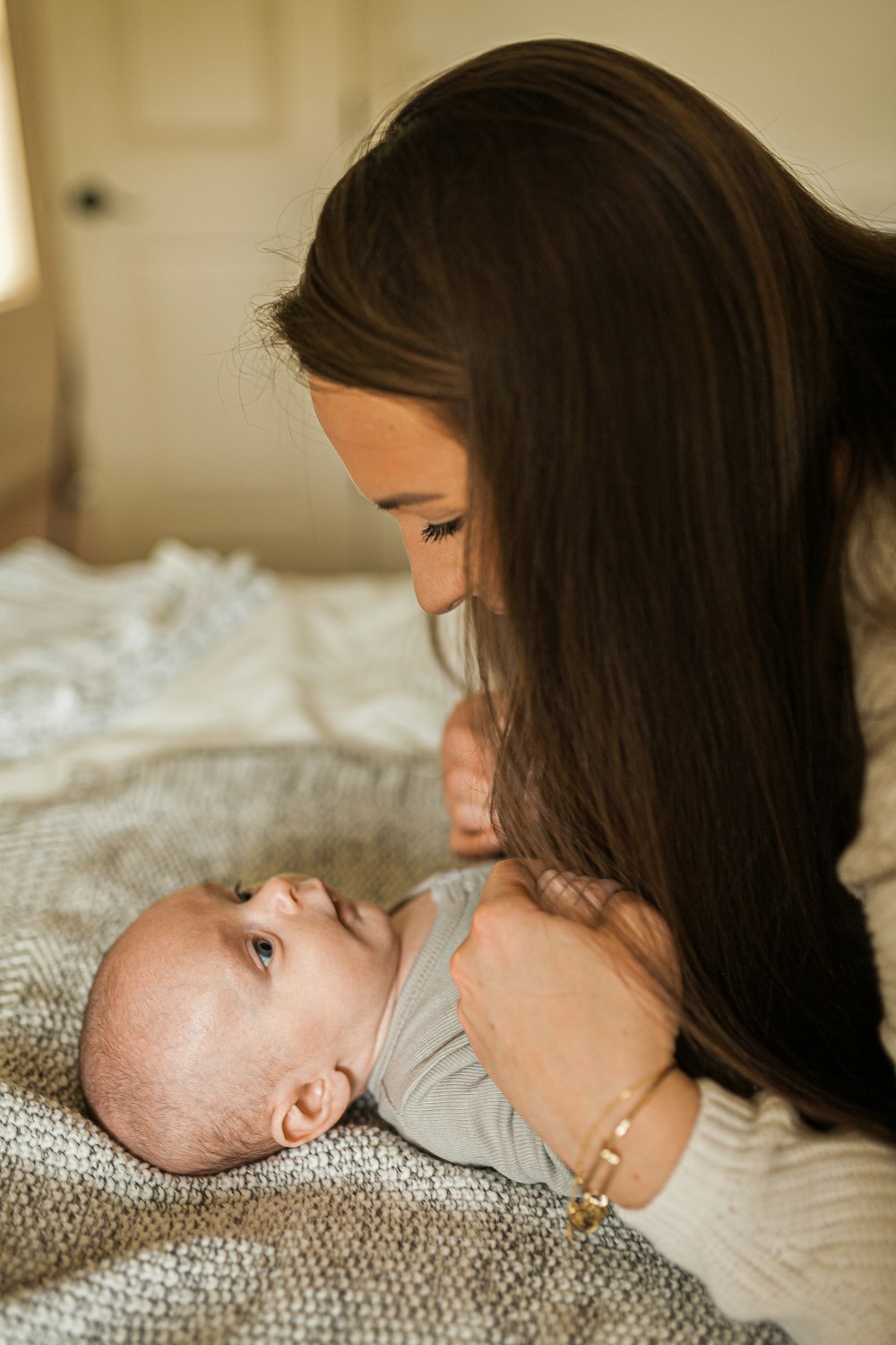 a woman holding a baby on top of a bed