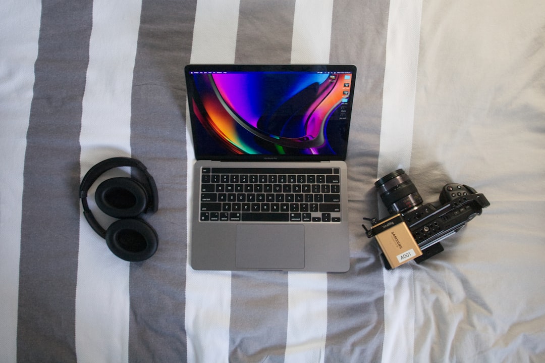 a laptop computer sitting on top of a bed next to a camera,