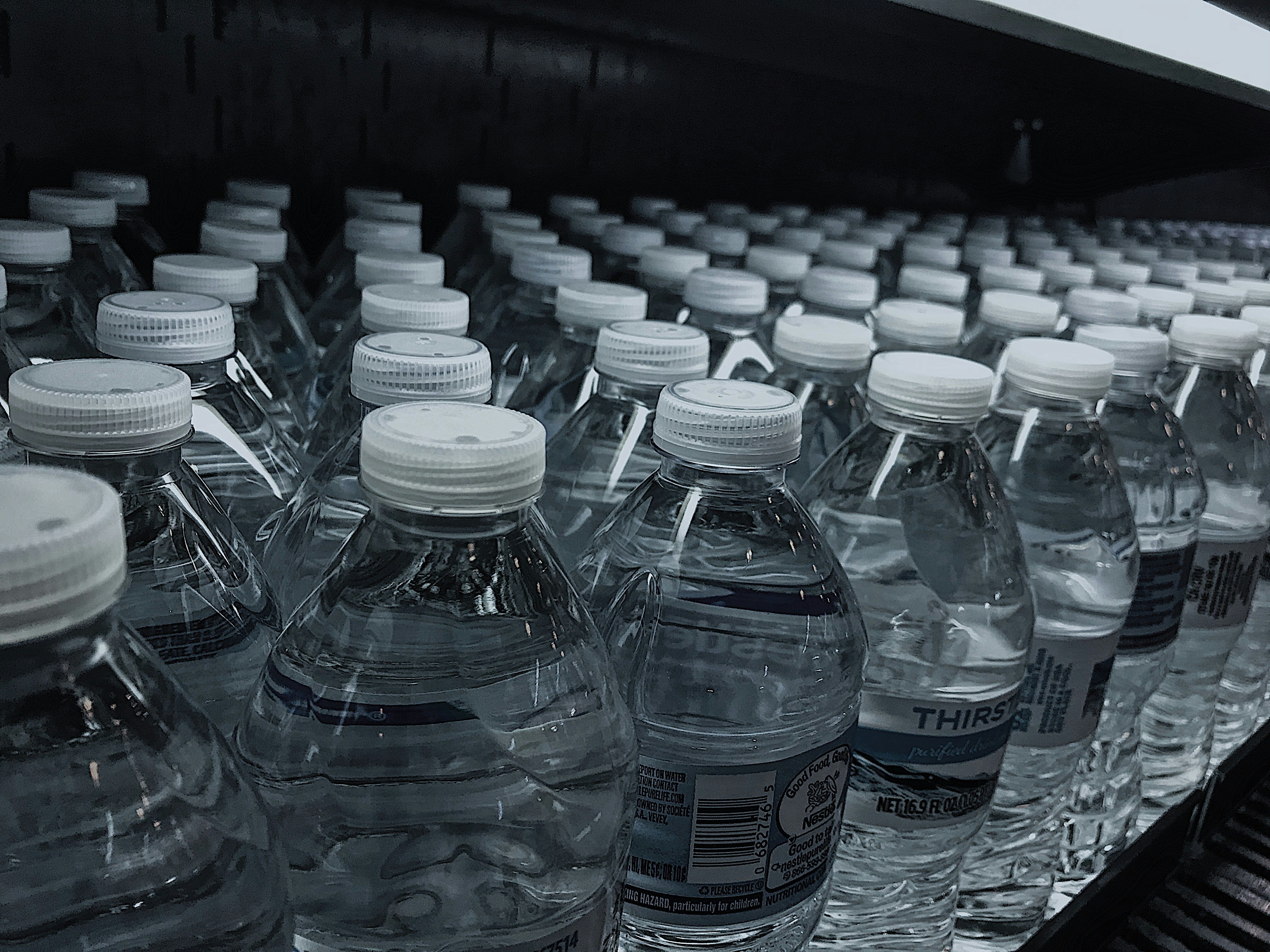 Clear water bottles arranged neatly on white background