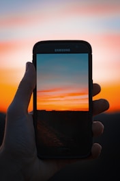 A vibrant photo of a travel influencer capturing a sunset with a smartphone.