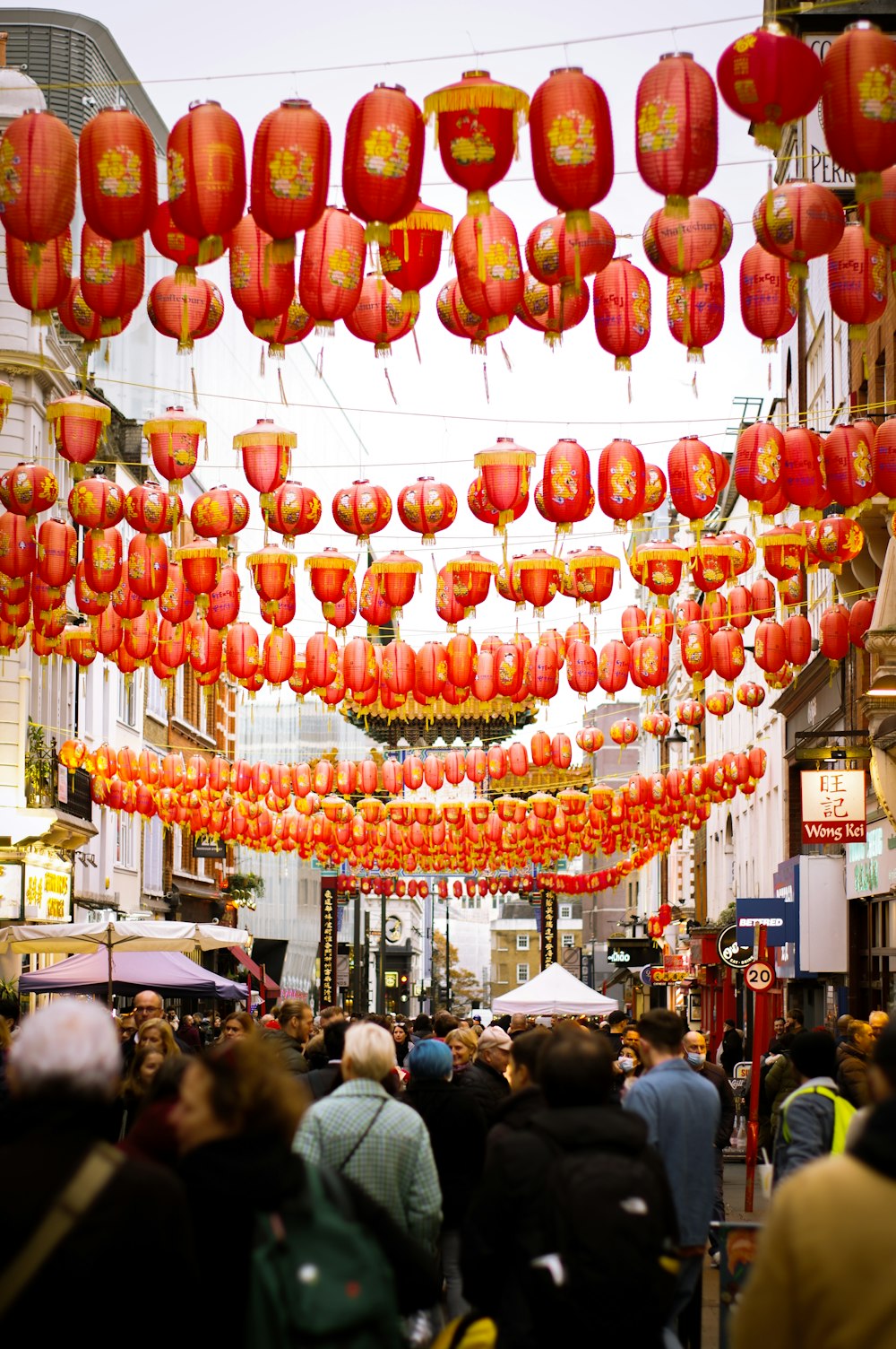 a group of people walking down a street under red lanterns