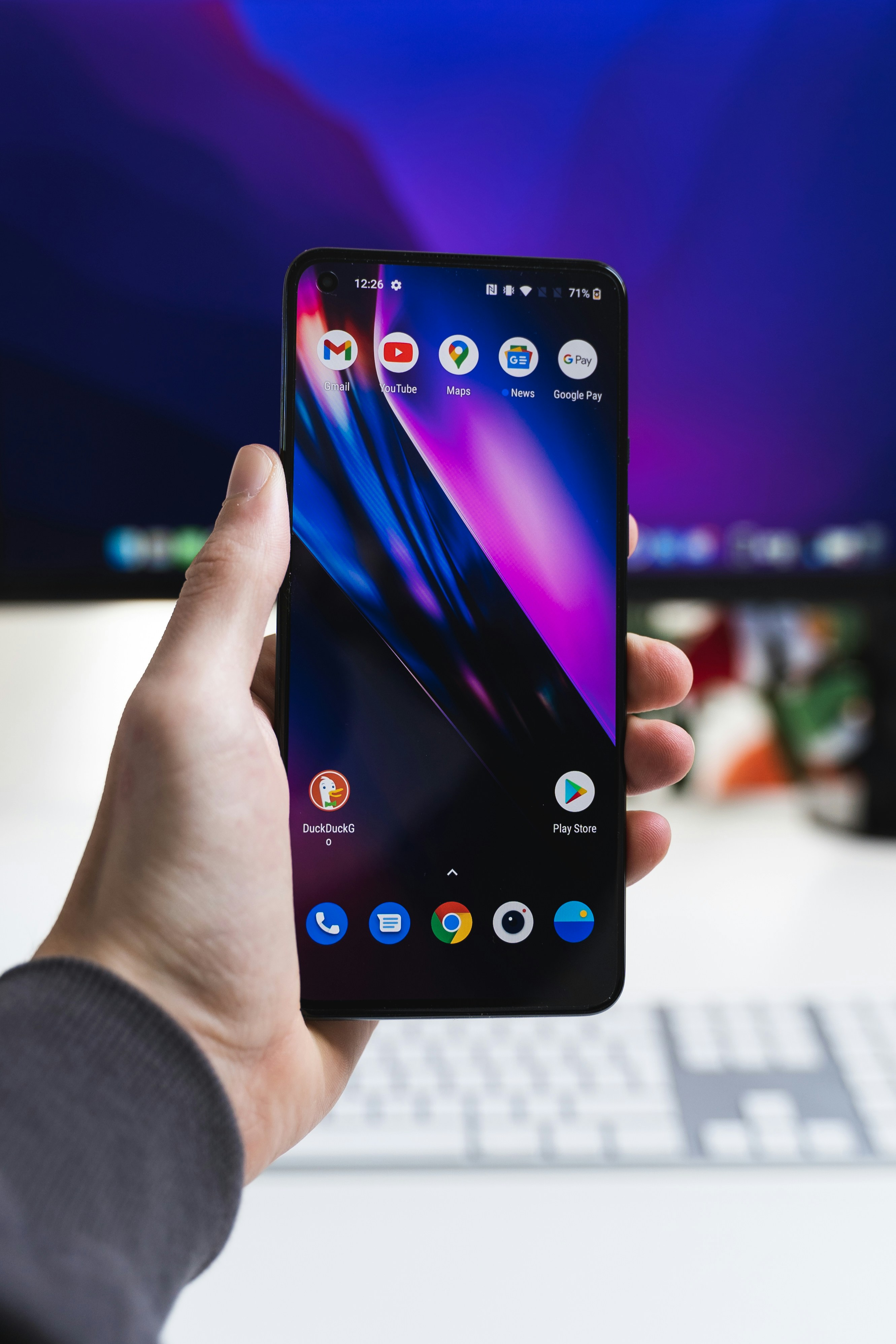 Hand holding an Android smartphone with Google Play Store icon visible