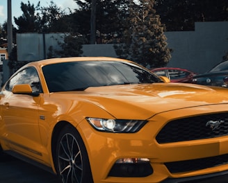 a yellow mustang car parked in a parking lot