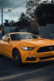 a yellow mustang car parked in a parking lot