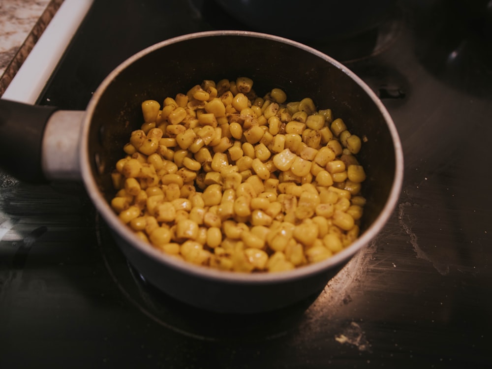 a pot filled with corn sitting on top of a stove