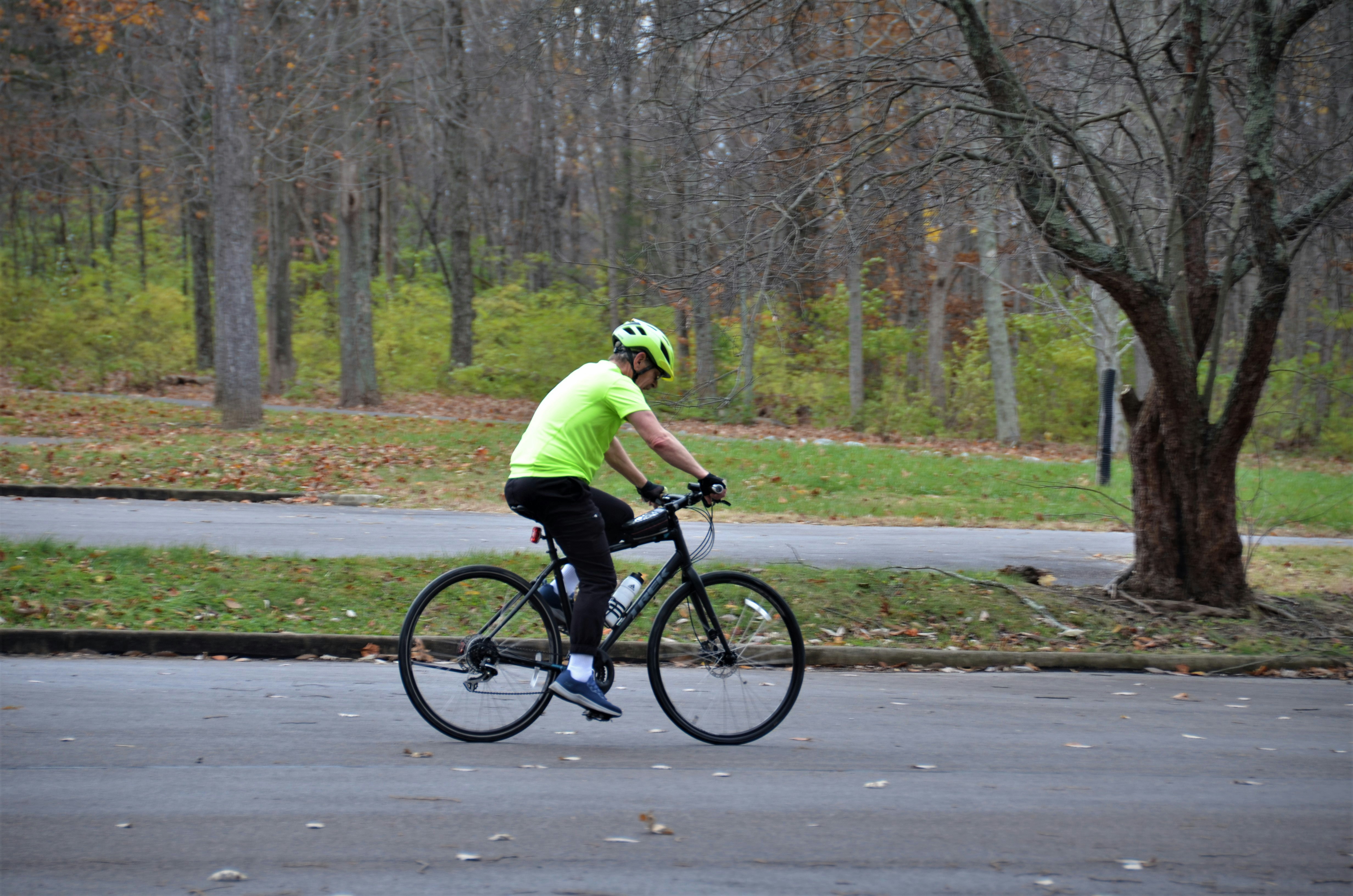a man riding a bike down a street next to a forest