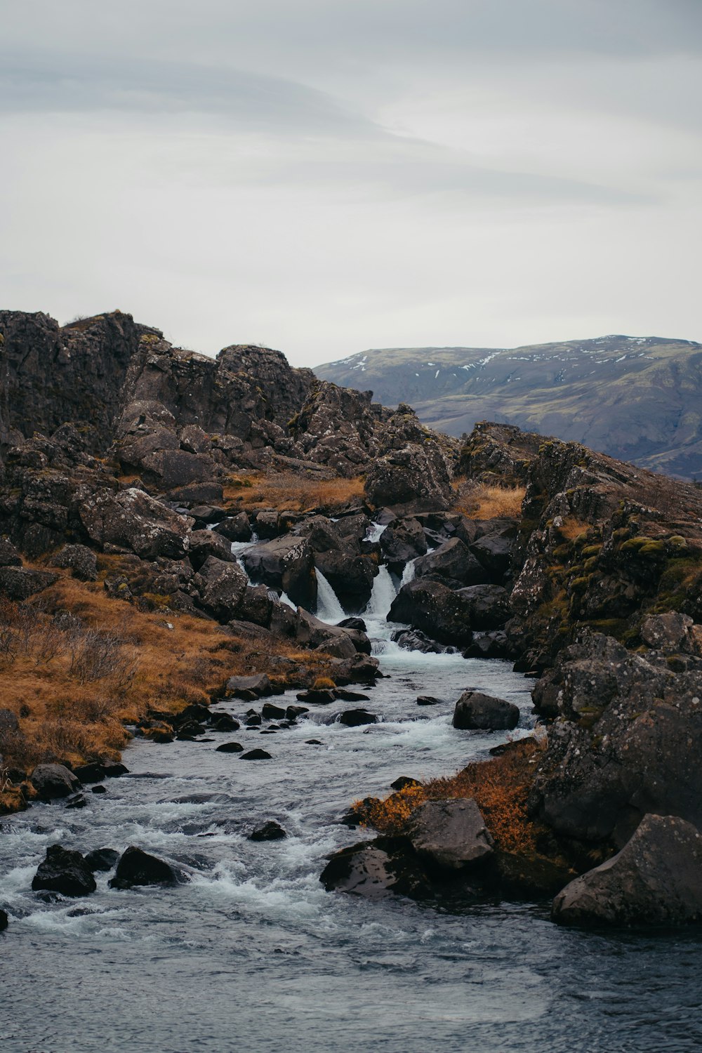 a stream running through a rocky landscape with a mountain in the background