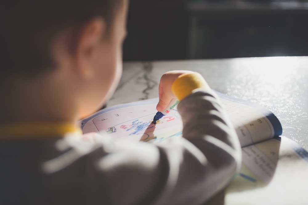 a young boy is drawing on a piece of paper