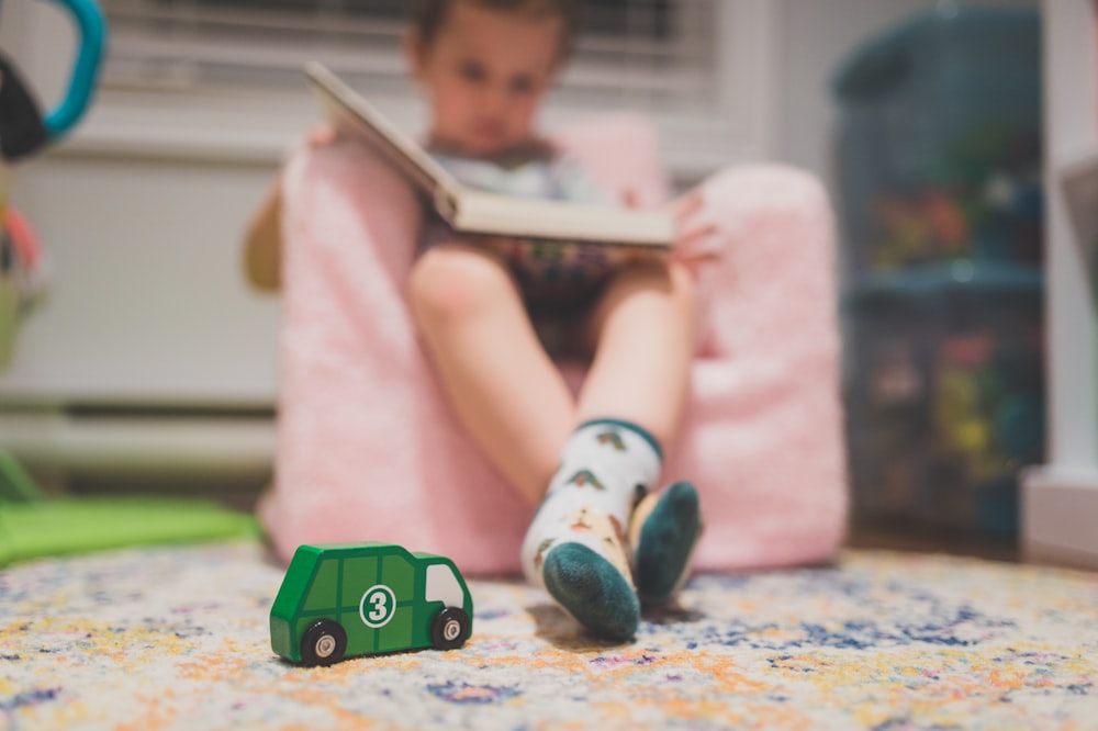 a little girl sitting in a chair reading a book