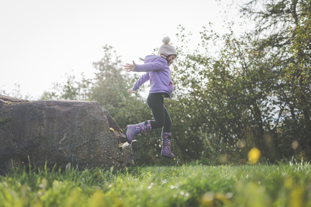 a young girl is running in the grass