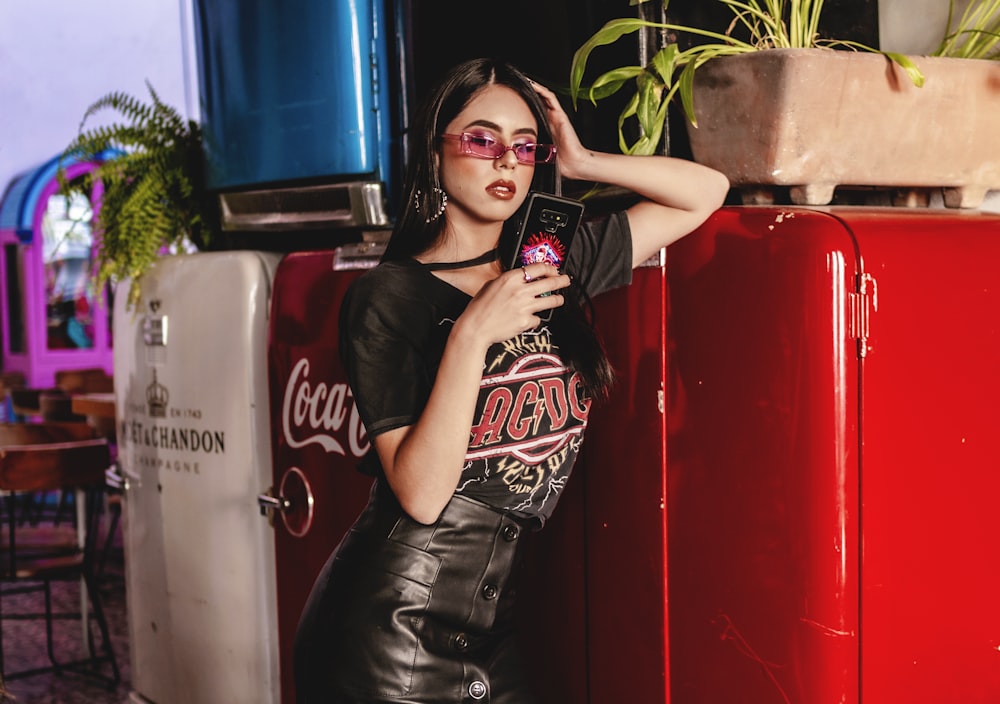 a woman in a leather dress leaning against a red refrigerator