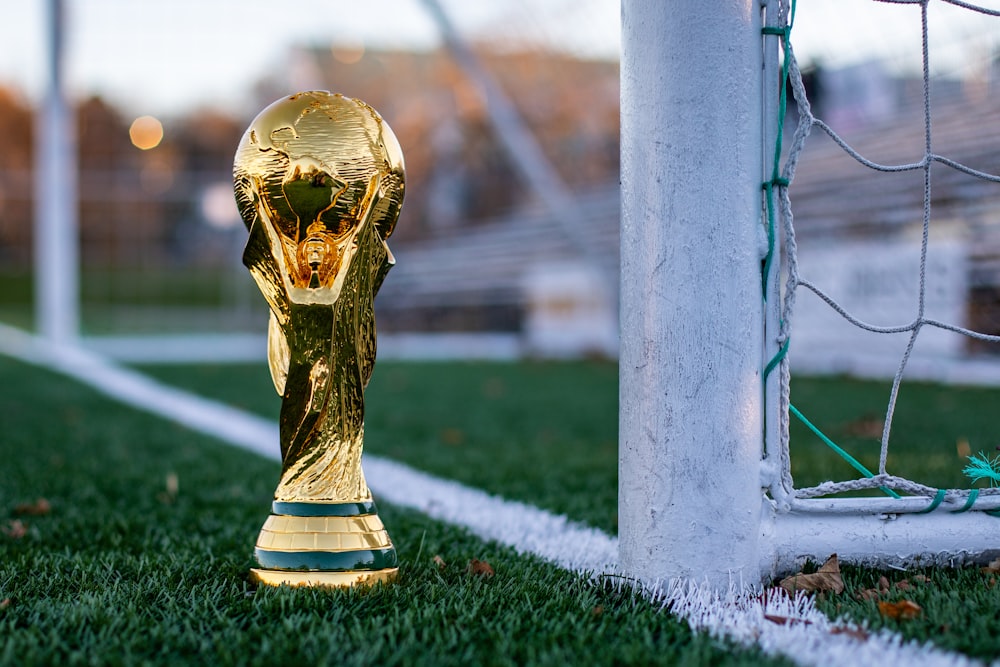 a golden soccer trophy sitting on top of a soccer field