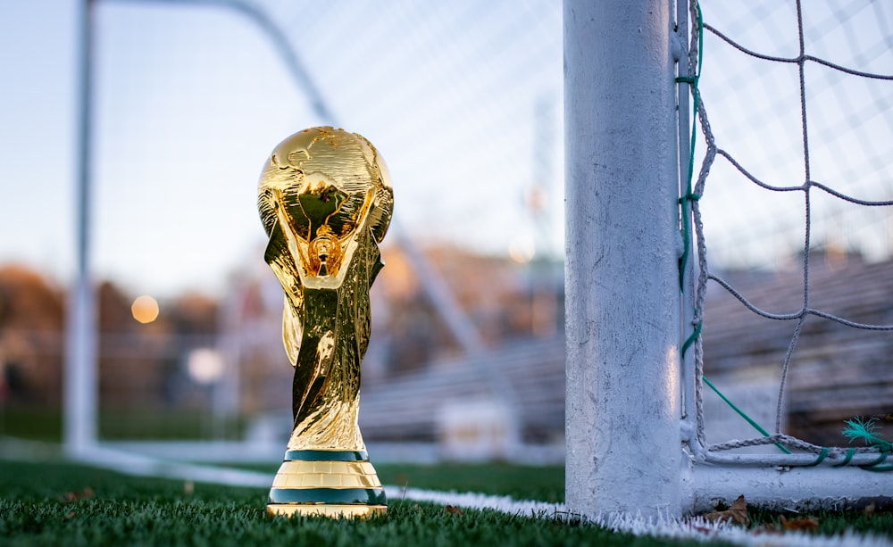 a golden soccer trophy sitting on top of a soccer field