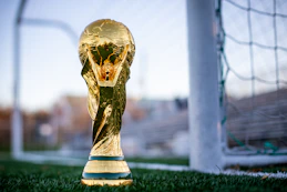 a golden soccer trophy sitting on top of a field