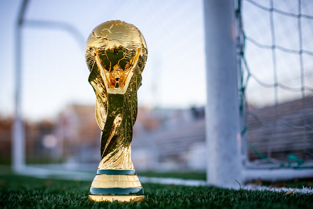 a golden soccer trophy sitting on top of a field