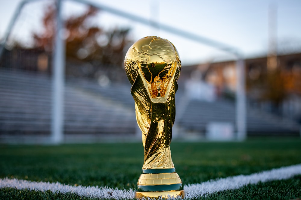 a golden trophy sitting on top of a soccer field