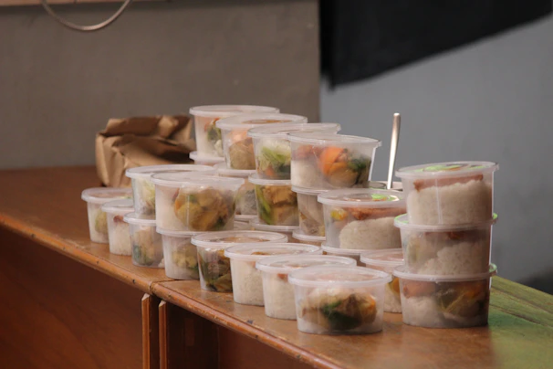 A close-up of colorful reusable plastic food containers neatly stacked in a bright kitchen setting.