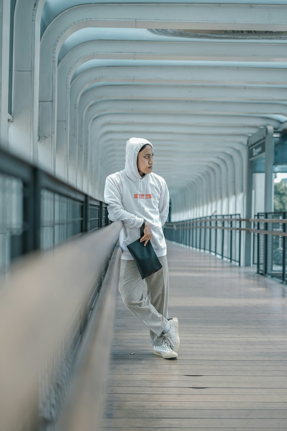 a man in a white hoodie is standing on a bridge