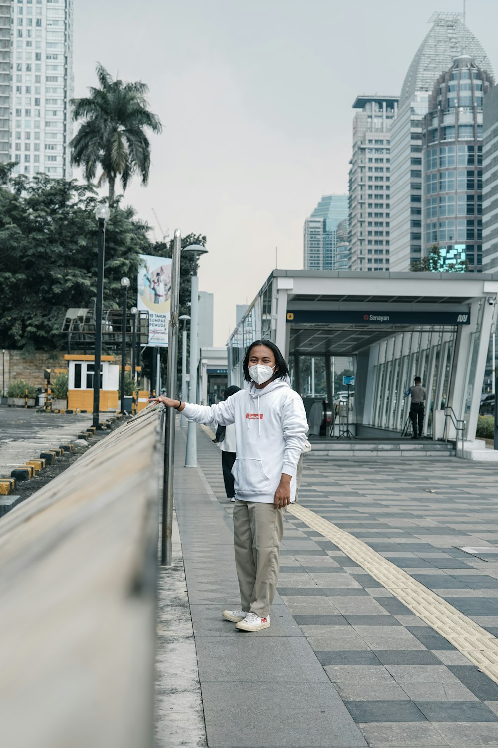 a man wearing a face mask standing on a sidewalk