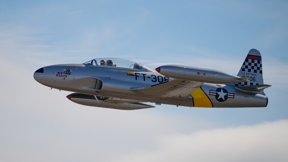 a silver fighter jet flying through a blue sky