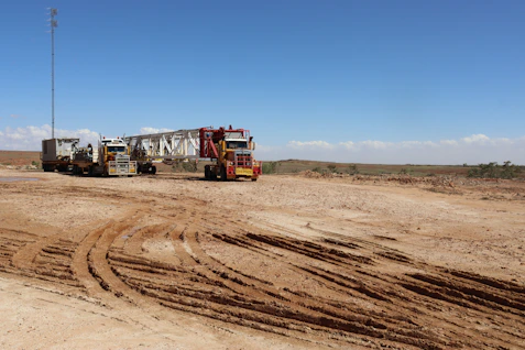 A heavy-duty trailer loaded with oilfield equipment ready for transport on a dusty Texas road.