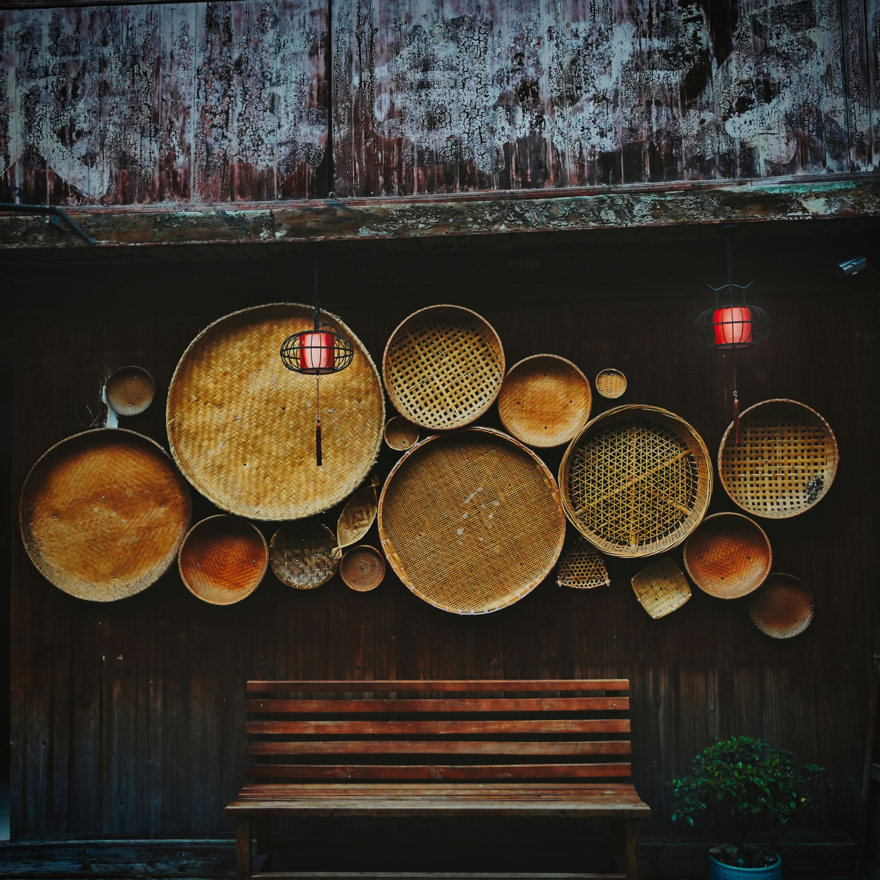 a wooden bench sitting in front of a wall covered in baskets