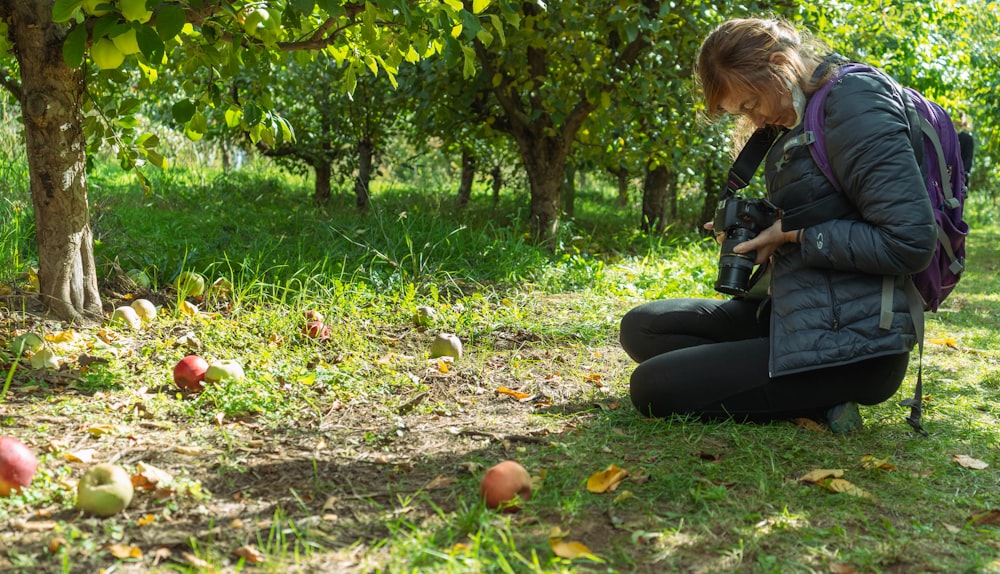 a woman kneeling down in the grass with a camera