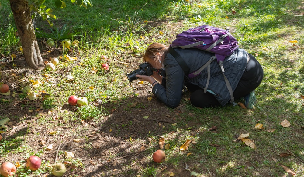 a woman kneeling down to pick apples from the ground