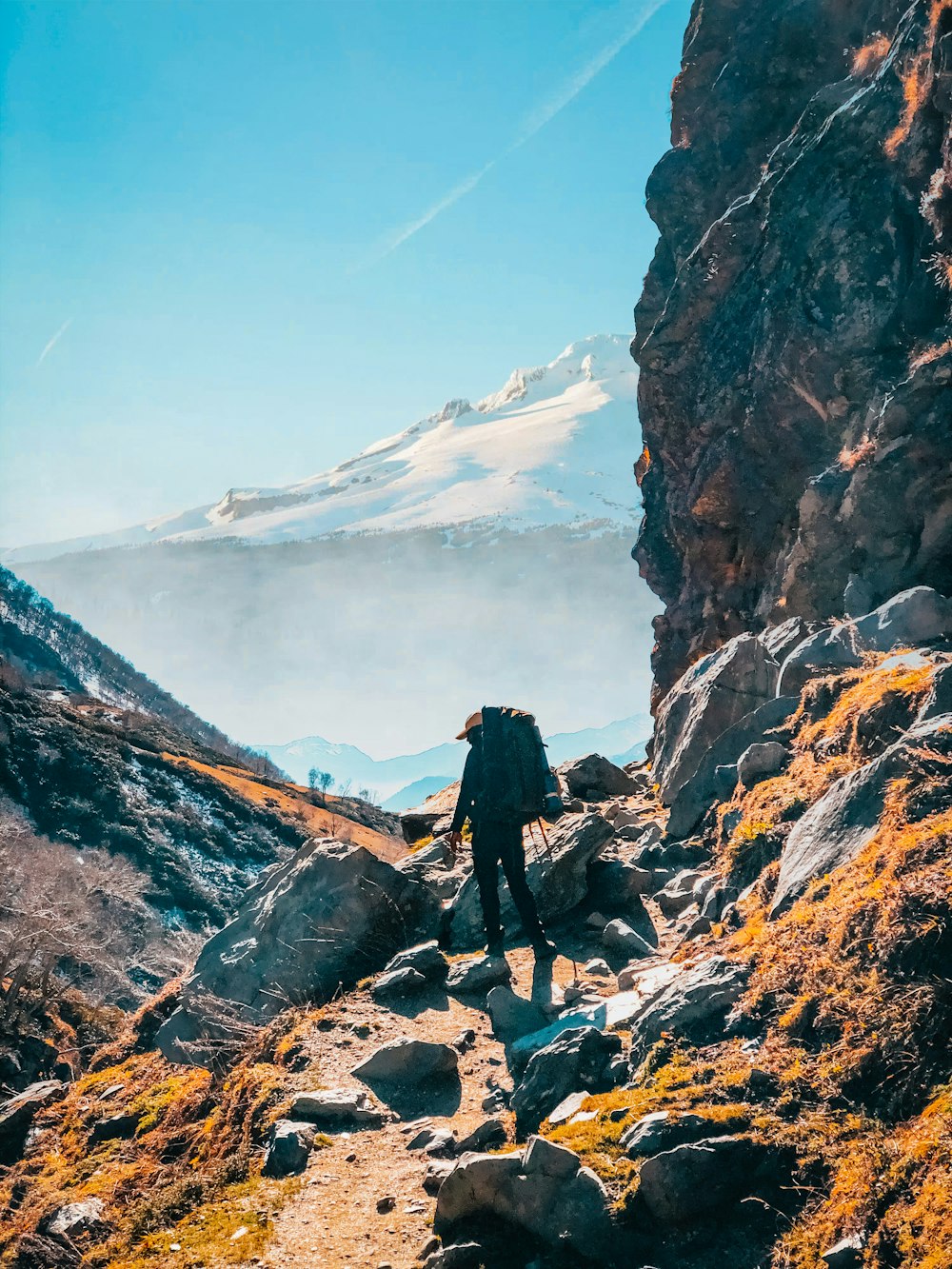 山を背景に岩だらけの小道をハイキングする人