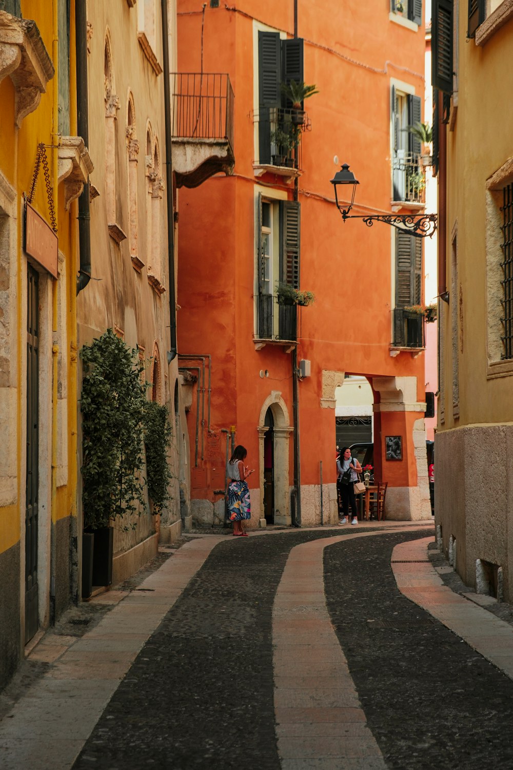 a narrow street with people sitting on the windows