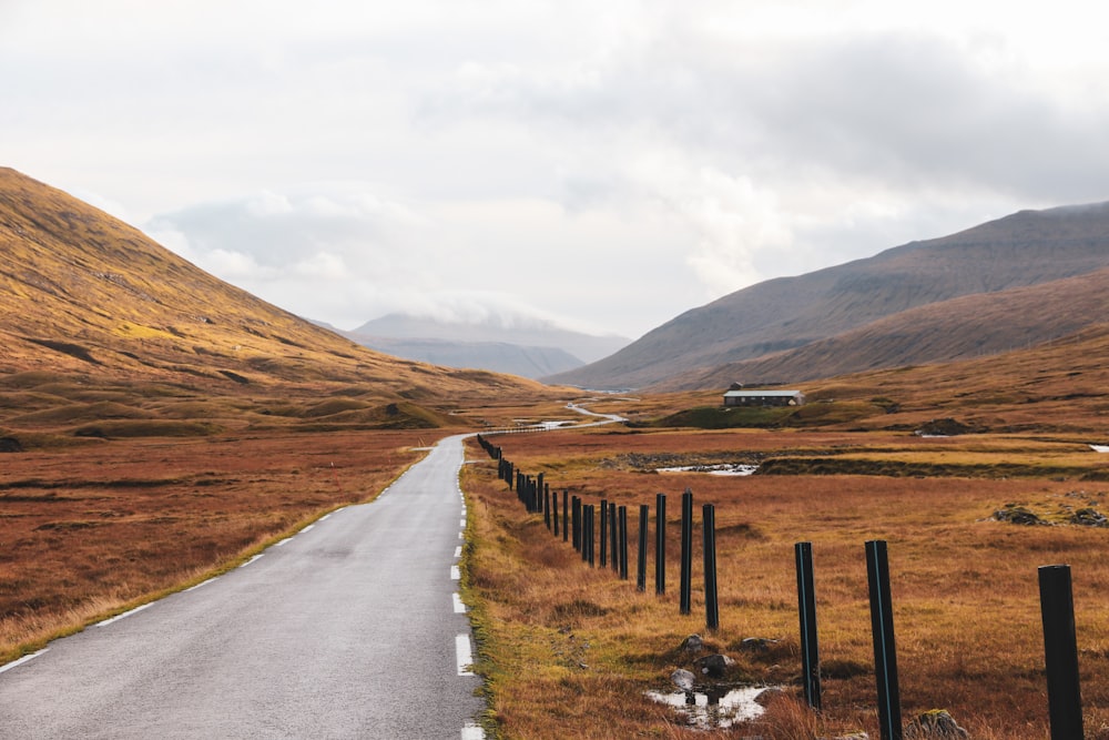 a road in the middle of a field with mountains in the background