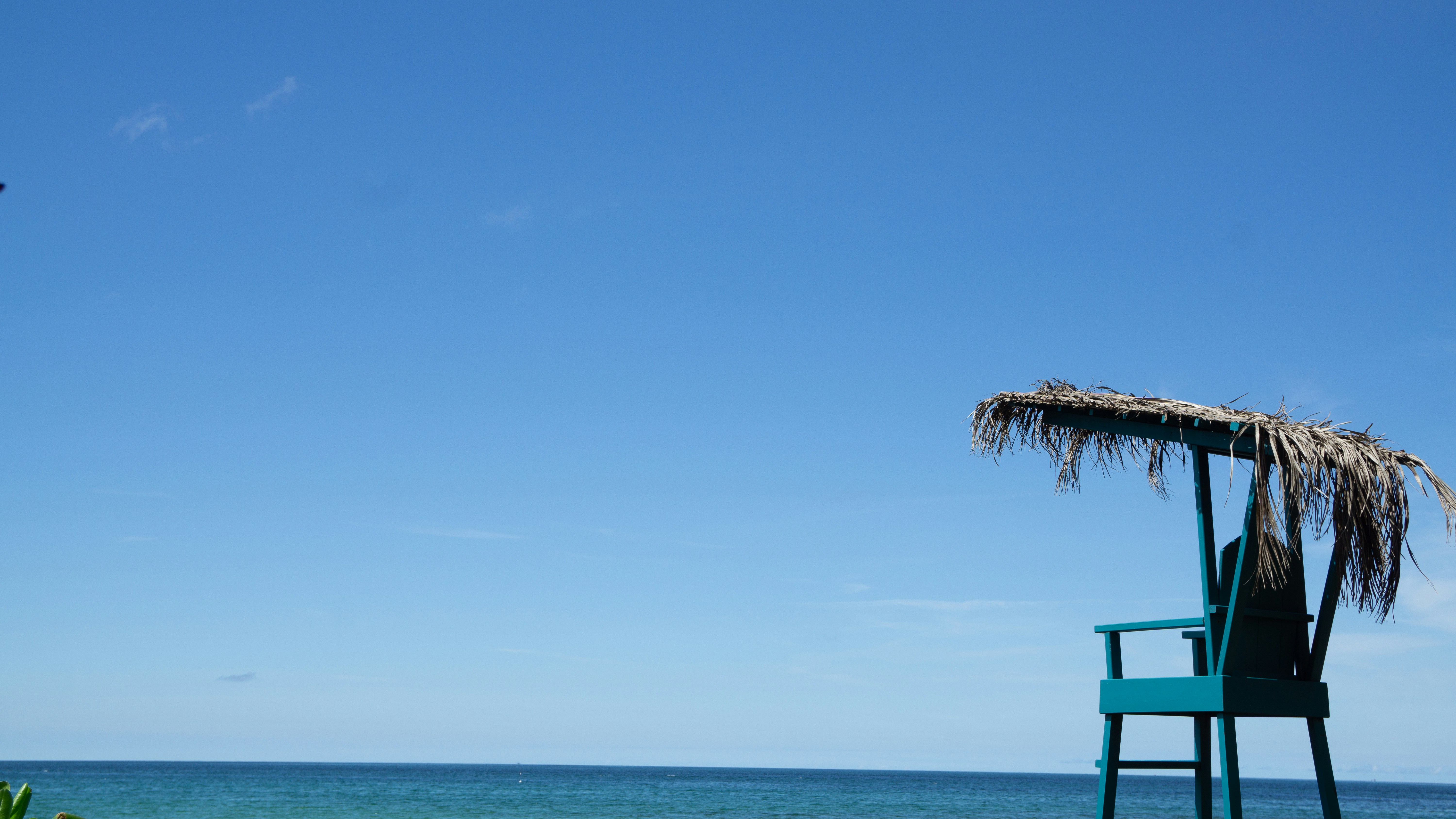 A chair sitting on top of a beach next to the ocean photo – Free Blue ...