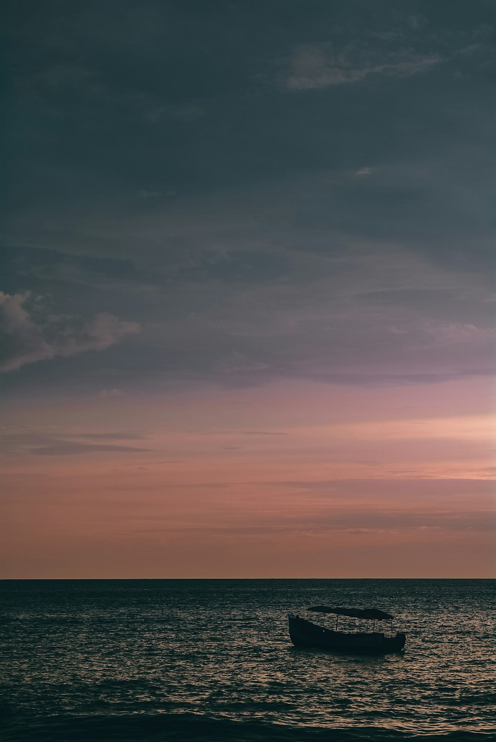 Un bateau est sur l’océan au coucher du soleil