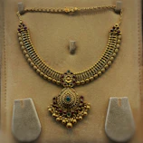 Close-up of a sparkling gold necklace with intricate designs on a velvet display