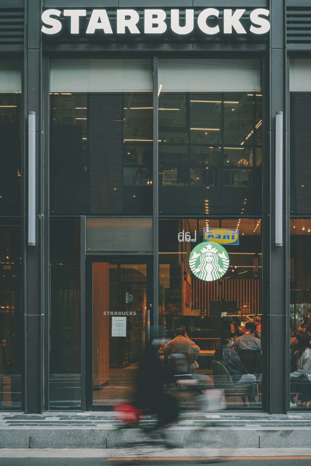 a man riding a bike past a starbucks shop