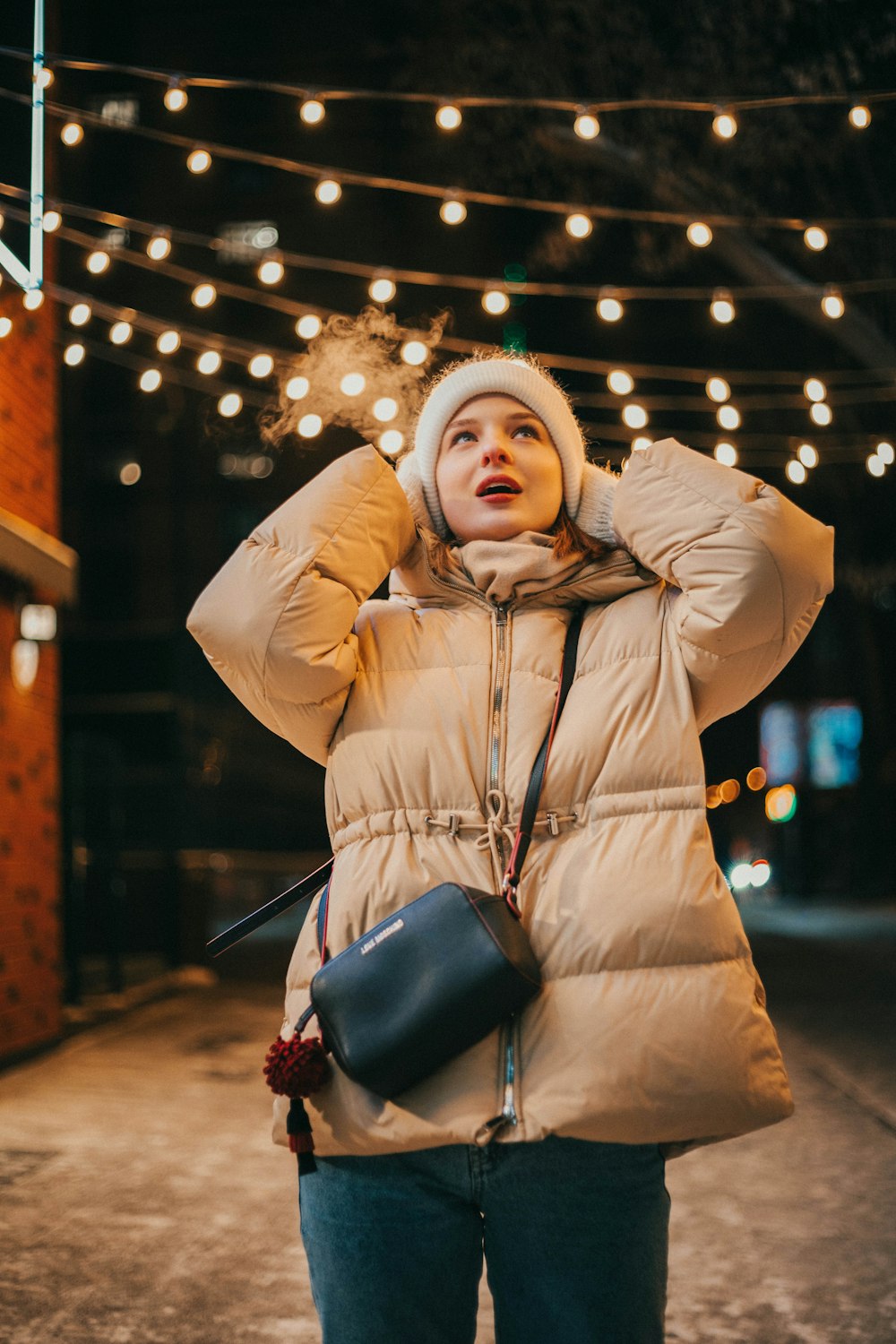 a woman in a puffy coat is holding her hands on her head