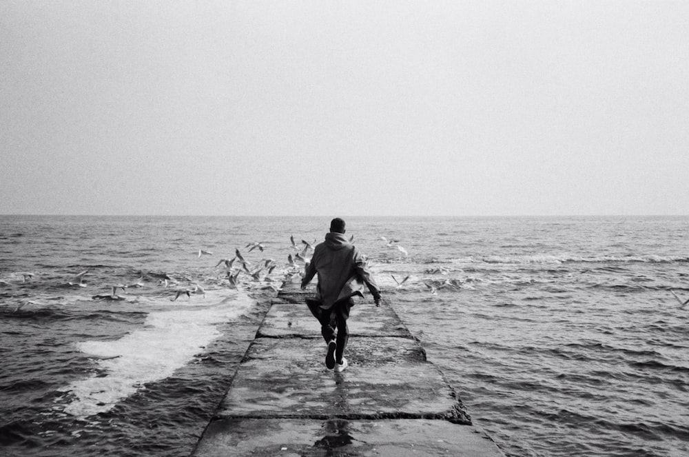 Un hombre caminando en un muelle sobre un cuerpo de agua