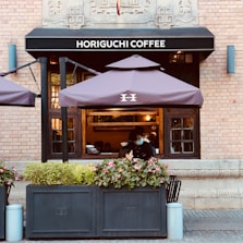 a woman sitting at a table in front of a coffee shop