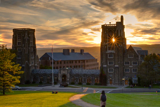 A historic university building bathed in warm sunlight with students walking nearby