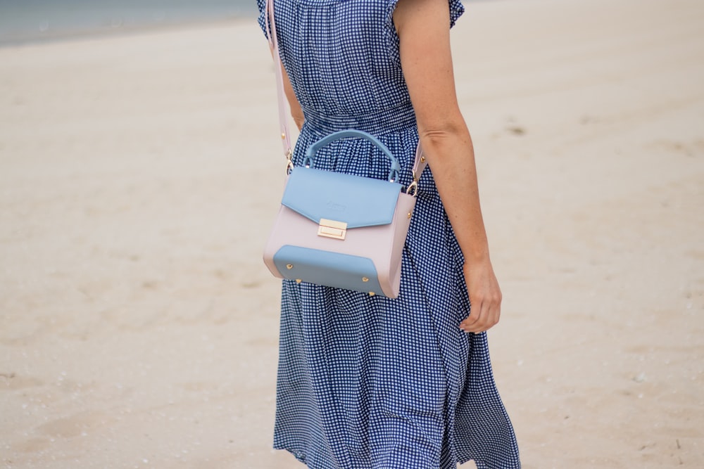 a woman in a blue dress carrying a blue and white purse