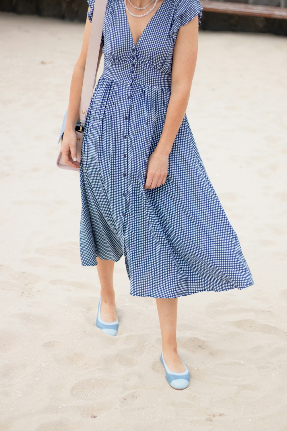 a woman in a blue dress is walking on the beach