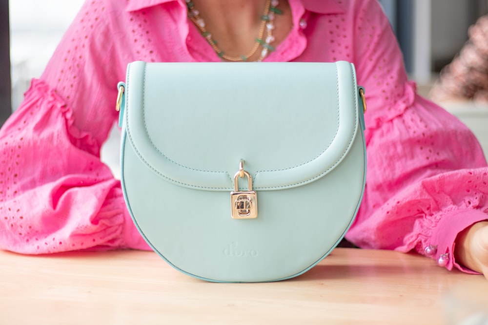 a woman sitting at a table with a blue purse