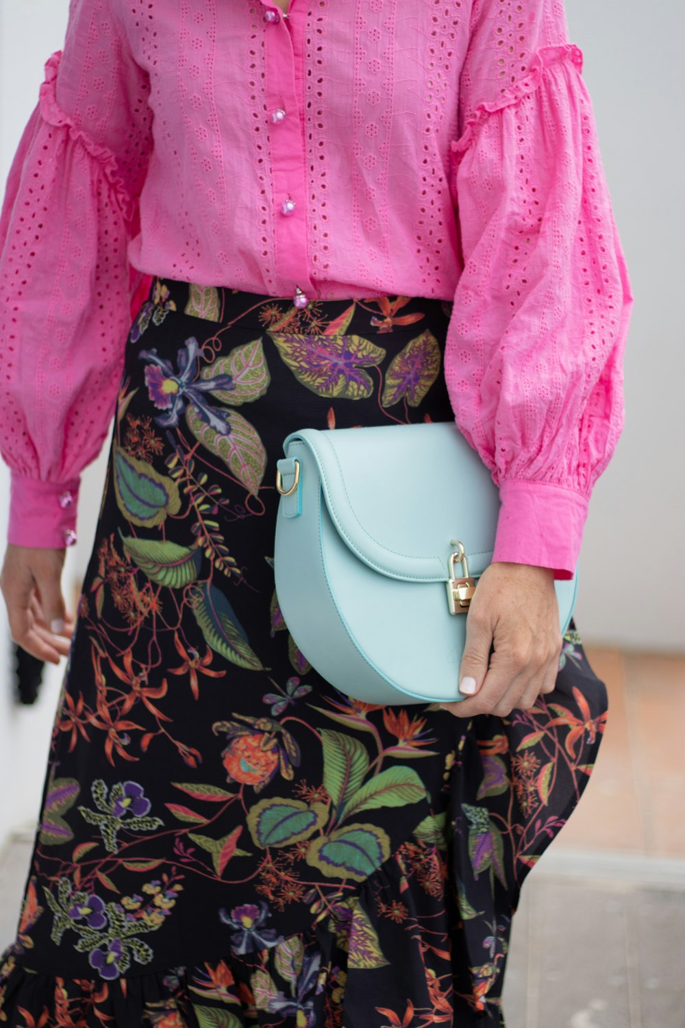 a woman wearing a pink shirt and a blue purse